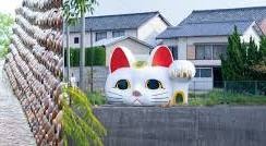 陶器の壁の先に見える大きな招き猫と家並み