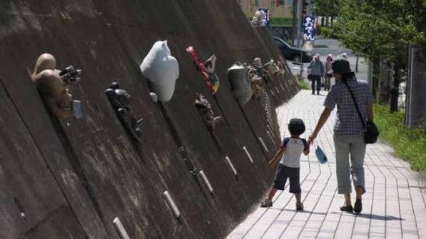 猫の焼き物が並ぶ常滑の歩道を歩く人々
